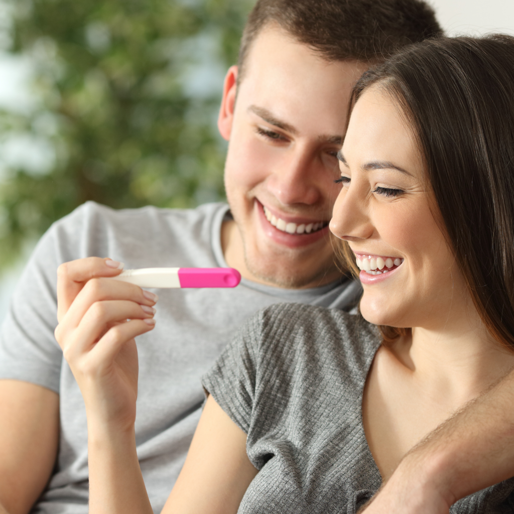 couple smiling holding pregnancy test